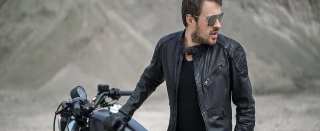 A man wearing motorcycle leather jacket and sitting on the harley bike