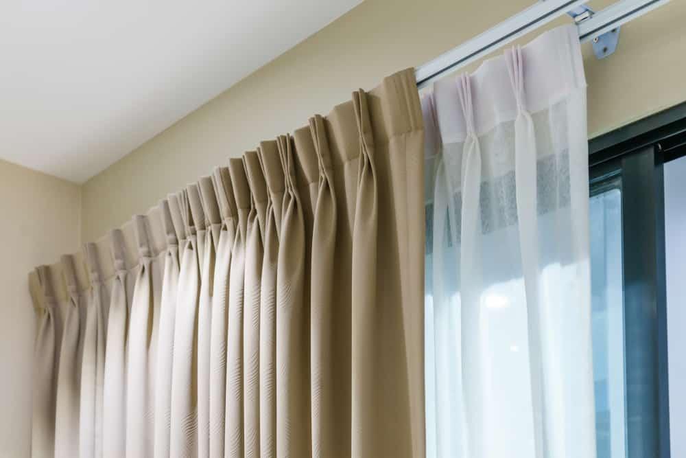 Professional tailor adjusting and hemming elegant curtains in a modern Dubai home